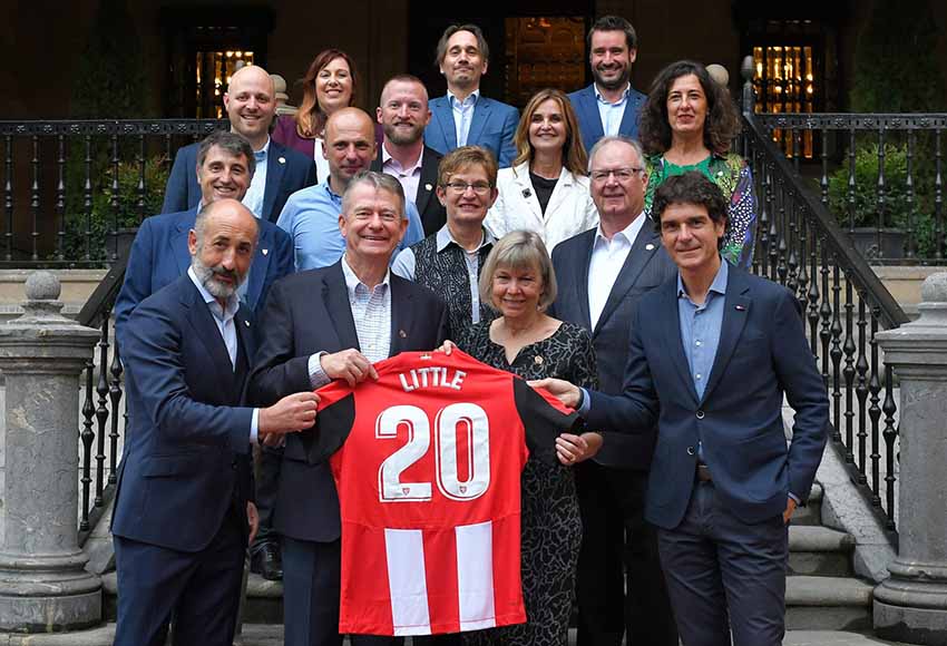 El gobernador Little y su mujer entre Unai Rementeria y Aitor Elizegi con la camiseta del Athletic portando el nombre de Little durante su visita a la sede de la entidad rojiblanca (foto Athletic)