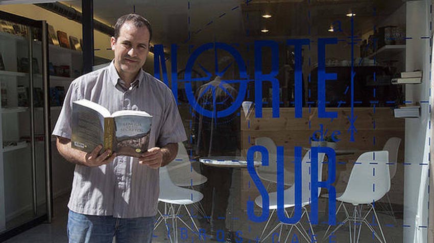 Mikel de Elguezabal with a book in front of his coffee shop-bookstore, Al Norte del Sur, located in Pamplona’s Consistorial Plaza (photo Unai Beroiz-Diario de Noticias)