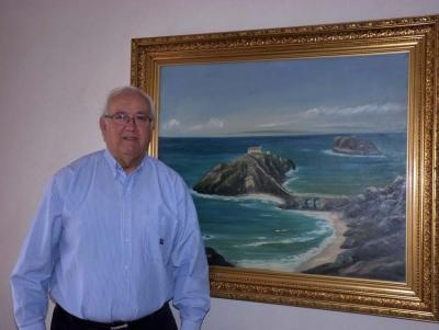 Basque-Chilean Luis Archibaldo Uriarte, whose father was from Bakio in front of a painting of San Jaun de Gaztelugatxe (photoEuskalKultura.com)