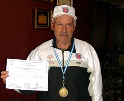 Roberto Navaridas, con el escudo del Centro Vasco de Chivilcoy en el pecho y el gorro, muestra el diploma que le acredita como campeón nacional argentino de 5.000 metros marcha-veteranos