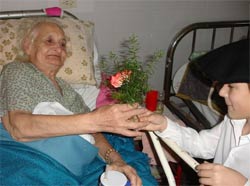 Santi, joven dantzari de Urrundik, obsequia con una flor y una sonrisa a una interna del Hospital, que le devuelve la sonrisa