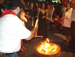 Arrojando pedazos de madera a la fogata y formulando deseos en presencia de Olentzero