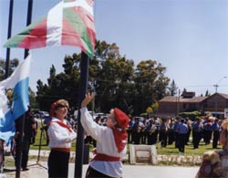 Isabel del Carmen Labiano y Sara Ibargoyen, vicepresidentes de 'Beti Aurrera Aberri Etxea', izan la ikurriña en la Plaza de los Inmigrantes viedmense