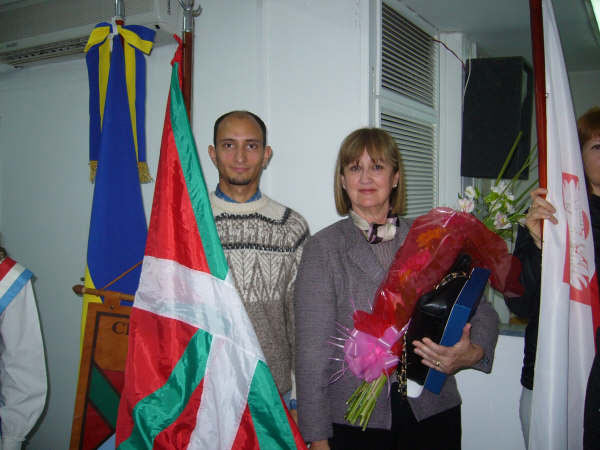 Nekane Echeverria junto al abanderado portando la bandera de su colectividad tras haber recibido la plaqueta y ramo de flores