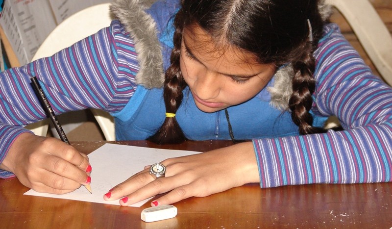 Una niña, concentrada, realiza su tarjeta de felicitación navideña (fotos Haize Hegoa)