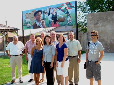 Jaurlaritza ordezkaritza eta euskal komunitateko buruzagiak Mountain Home-ko 'Basque Park' edo euskal Parkean, atzean euskal murala eta eskuinean pilotalekuaren zatitxo bat ikusten dela (argazkia MountainHomeNews)