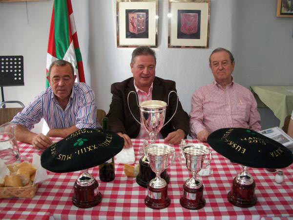 Álvaro del Corral, presidente de la federación de euskal etxeas de España, Julián Celaya, director para los Ciudadanos y las Colectividades Vascas, y Jon Zaballa, presidente de Euskal Etxea de Madrid, junto a los trofeos del campeonato.