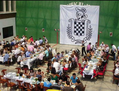 View of the Basque club's fronton with tables full of diners and the Baztan insignia 