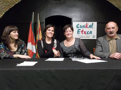 Ezkerrean, Bartzelonako Euskal Etxeko lehendakariordea, Sara Galar; eta lehendakaria, Oihane Astui, hitzarmena sinatu ostean eskua ematen Lourdes Auzmendi Hizkuntz Politikarako sailburuordearekin; ondoan Iñaki Uribe, HABEko zuzendaria (argazkia HABE)