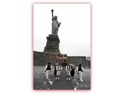 Foto histórica de un grupo de dantzaris a los pies de la Estatua de la Libertad, con la ikurriña y la bandera norteamericana (foto EENY)