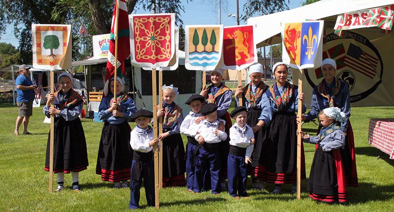 Los jóvenes miembros del grupo de danzas local Beti Alai frente al 'poblado vasco' del festival (Foto: OBC)