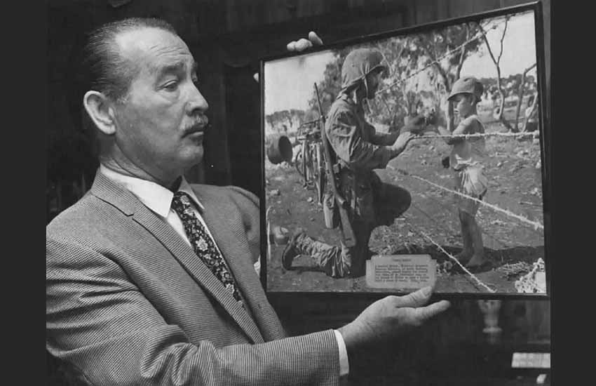 Federico Claveria observes an iconic image of WWII in which he appears in 1944, giving candy to a child from Tinian boarding School (photo US Department of Defense, USMC)